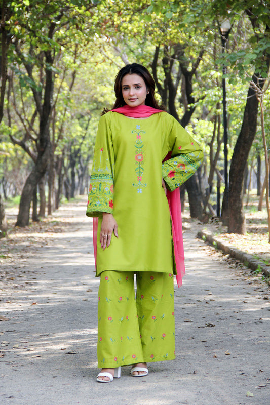 Woman in a green traditional outfit with pink dupatta standing on a path in a park.