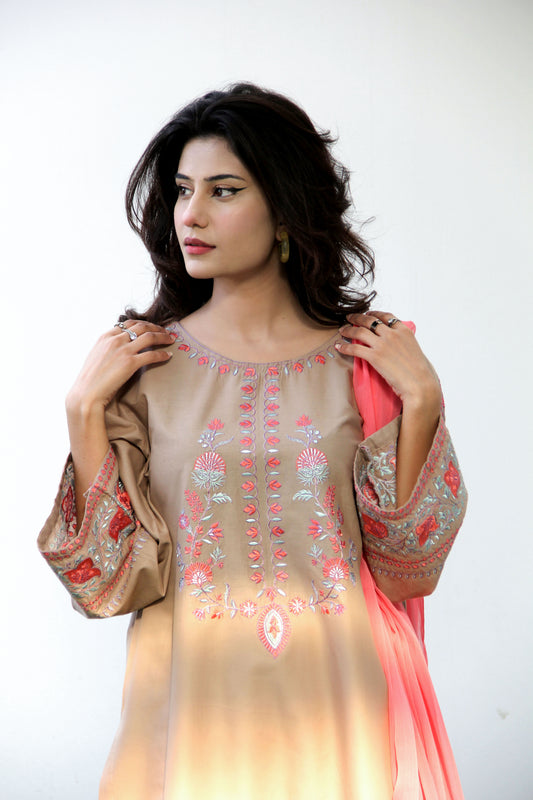 Woman wearing a beige and pink embroidered traditional outfit on a white background
