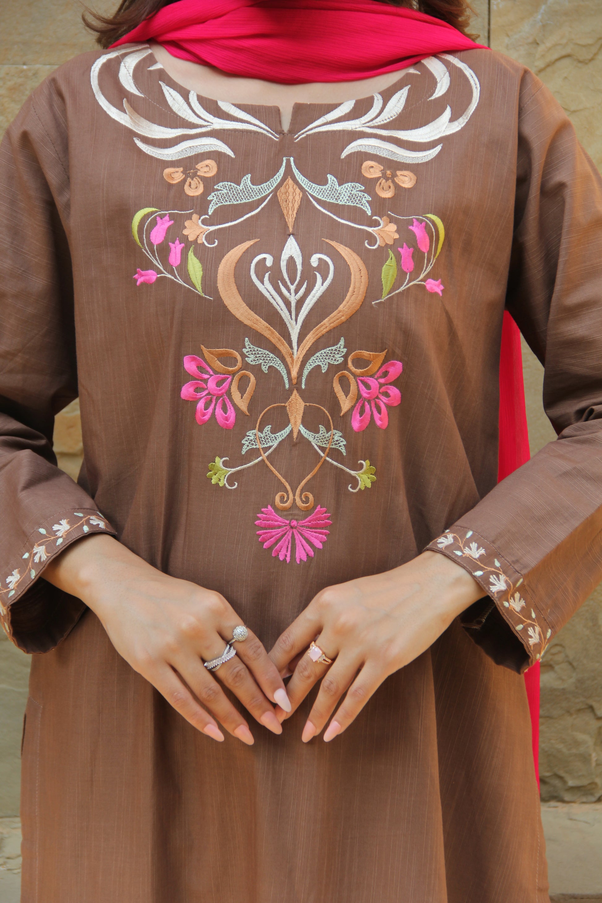 Brown garment with floral embroidery held by hands