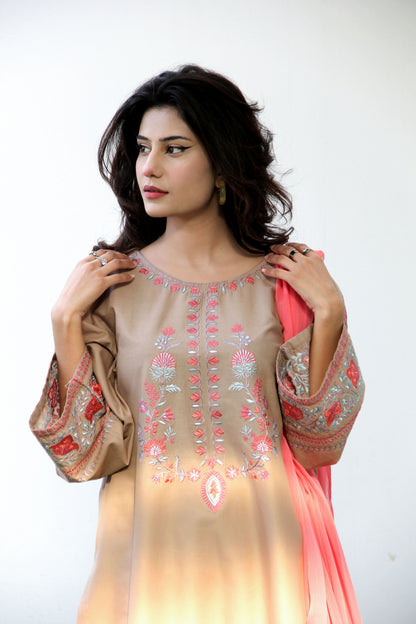 Woman wearing a beige and pink embroidered traditional outfit on a white background