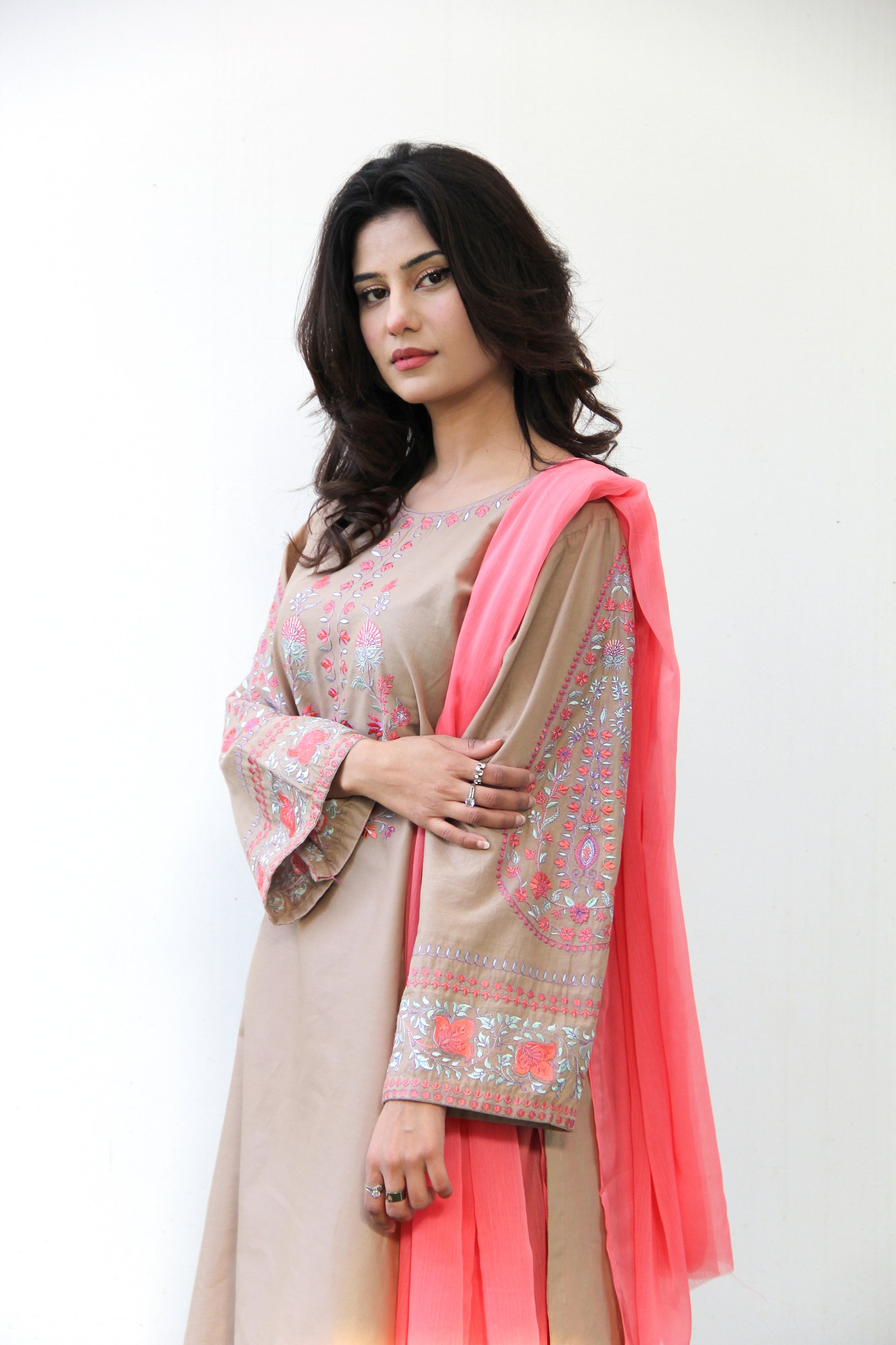 Woman wearing a traditional outfit with a pink dupatta against a white background