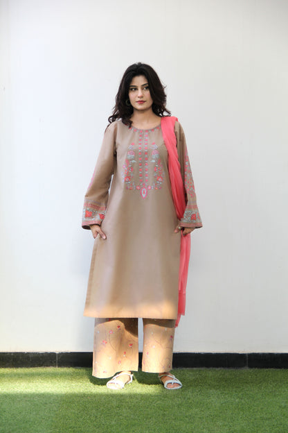 Woman wearing a beige kurta with pink accents against a white wall.